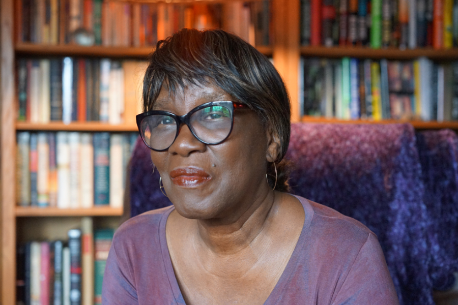 Patricia Smith sitzt in ihrem Wohnzimmer vor einem Bücherregal